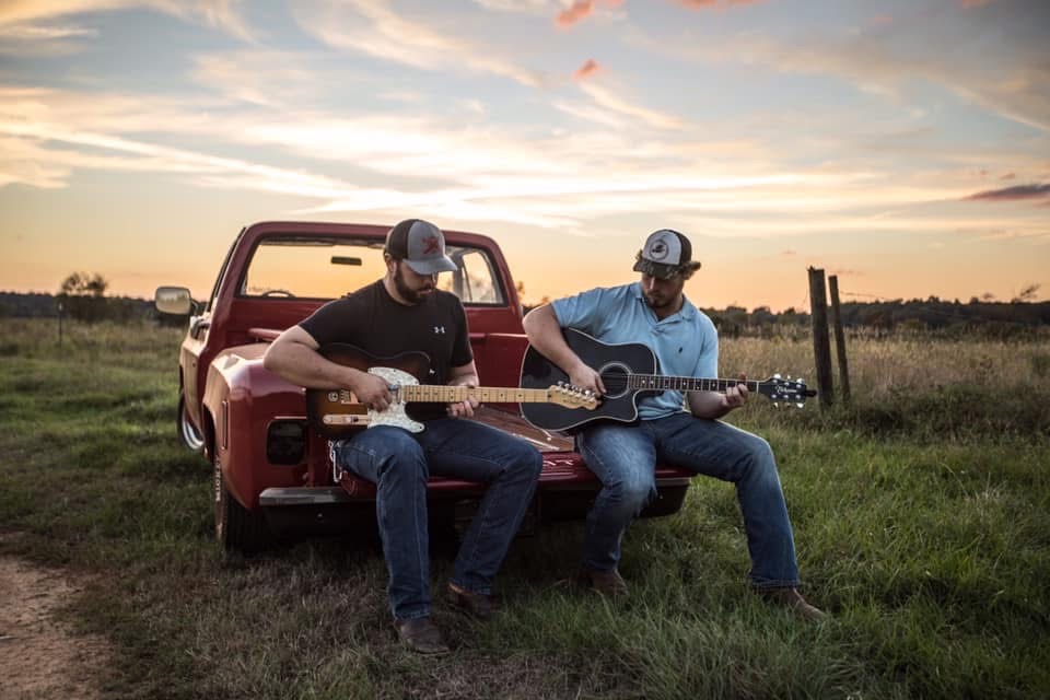 Guitars on a red pickup tailgate at sunset